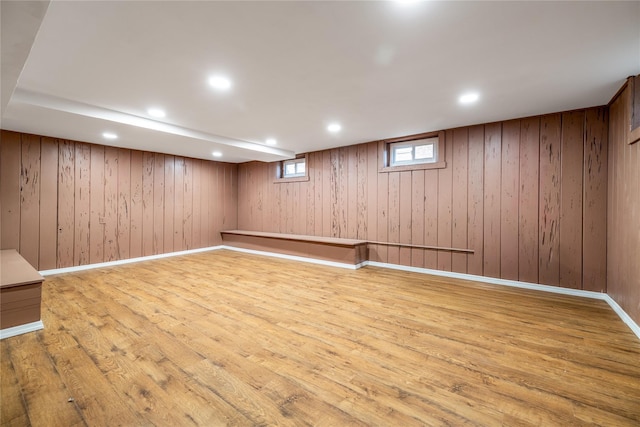 basement featuring light wood-style floors, recessed lighting, wood walls, and baseboards