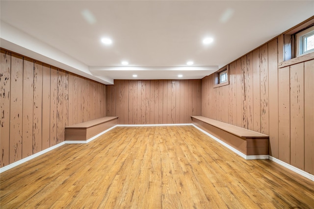 below grade area with baseboards, wooden walls, light wood-style flooring, and recessed lighting