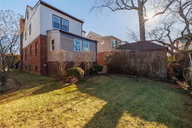 back of property featuring brick siding and a lawn