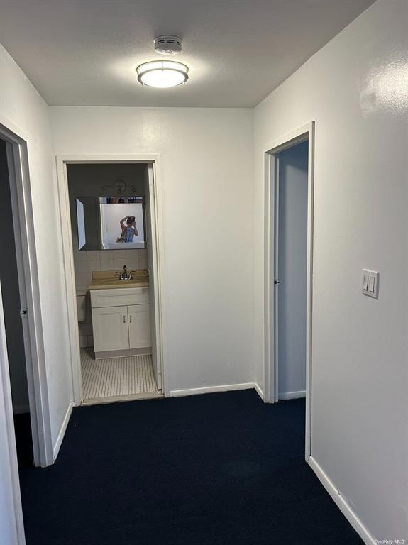 hall featuring dark carpet and sink