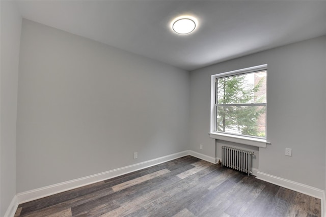 empty room featuring dark wood-type flooring and radiator heating unit