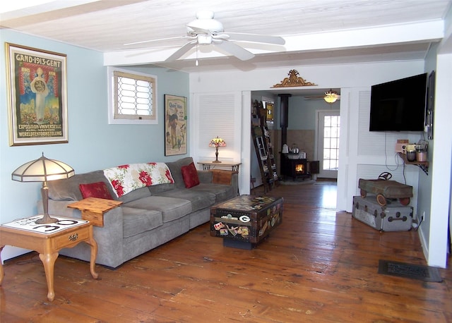 living room with a wood stove, a healthy amount of sunlight, ceiling fan, and wood-type flooring