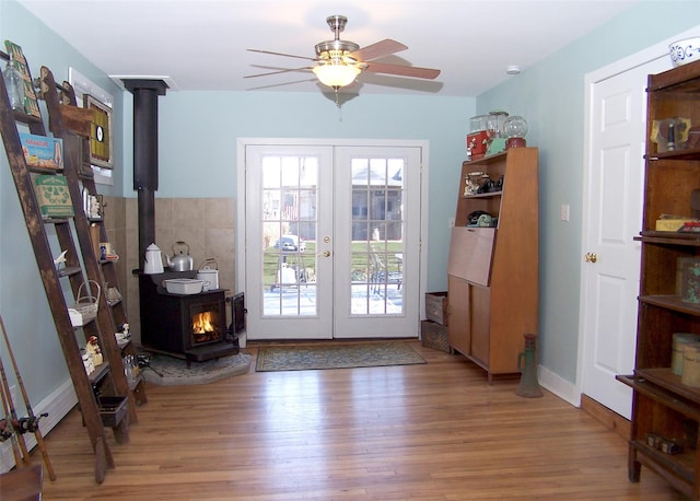 entryway featuring a wood stove, ceiling fan, wood finished floors, and french doors