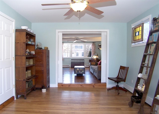 living area with light wood-style floors, baseboards, and a baseboard heating unit