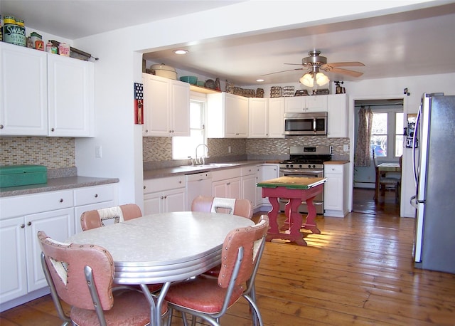 kitchen with stainless steel appliances, white cabinets, and hardwood / wood-style floors