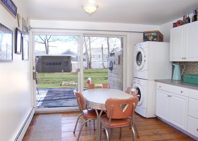 dining space featuring light wood-type flooring, stacked washer and dryer, and a baseboard heating unit