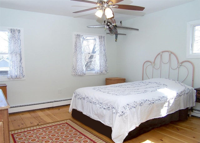 bedroom with a baseboard radiator, ceiling fan, and wood finished floors