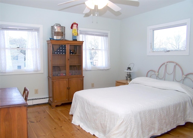 bedroom featuring a ceiling fan, a baseboard radiator, and light wood finished floors