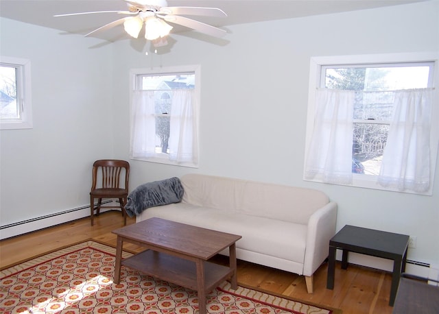 living room featuring light wood finished floors, ceiling fan, and a baseboard heating unit