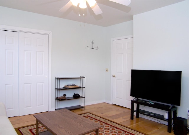 living area with baseboards, ceiling fan, and light wood finished floors