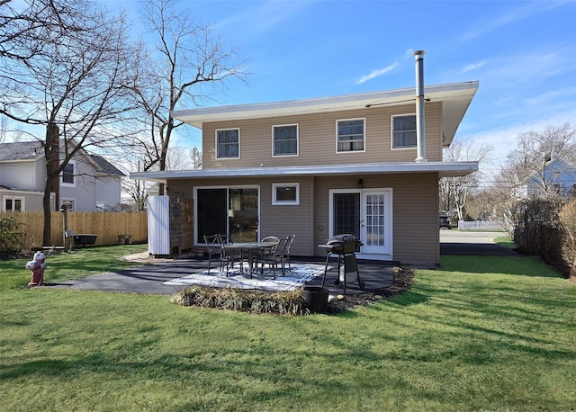 rear view of house featuring a patio area, fence, and a lawn