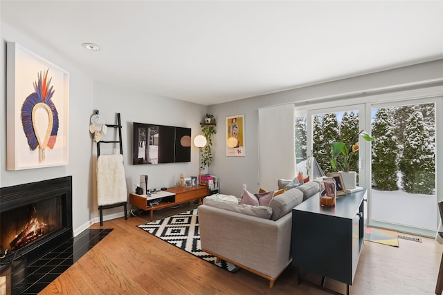 living room with a tile fireplace and wood-type flooring