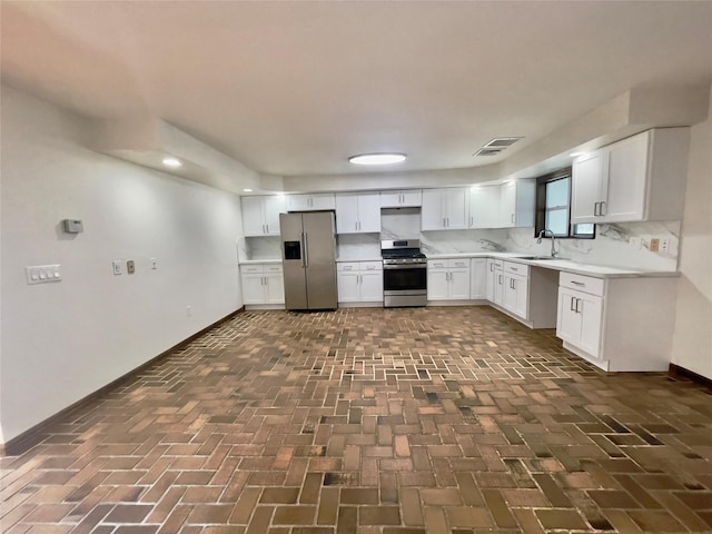 kitchen with visible vents, brick floor, a sink, stainless steel appliances, and white cabinets