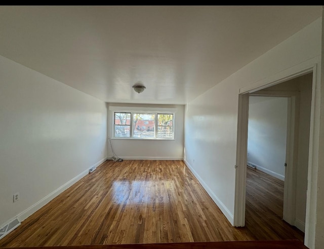 spare room with visible vents, baseboards, and wood finished floors