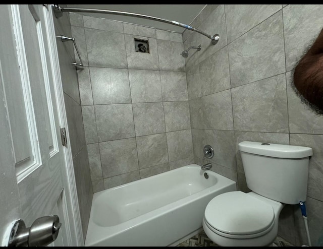 bathroom with toilet, bathtub / shower combination, and tile walls