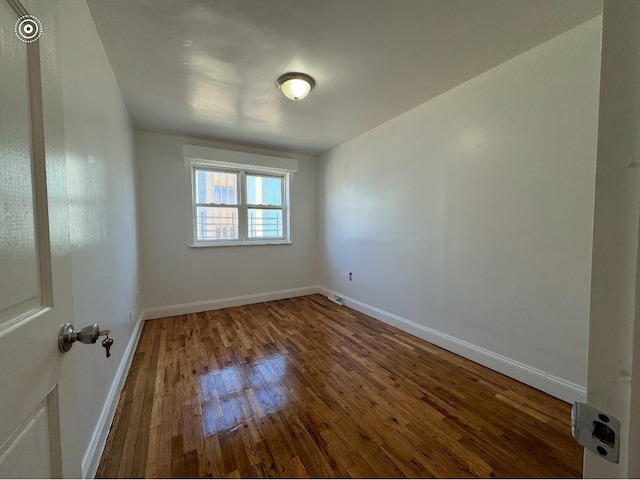 spare room featuring baseboards and wood finished floors