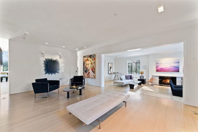 living area with light wood-style floors, a lit fireplace, and visible vents