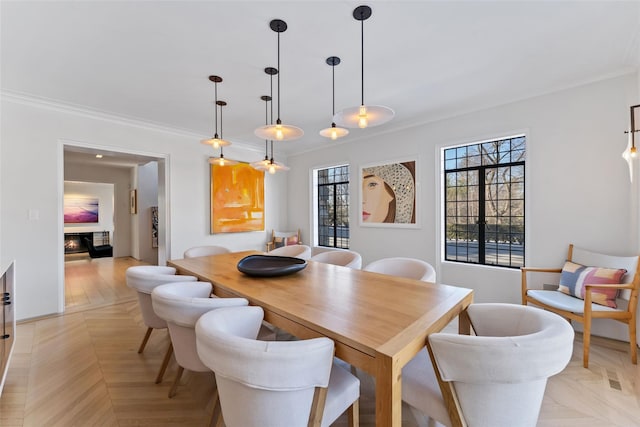 dining area featuring ornamental molding and a glass covered fireplace