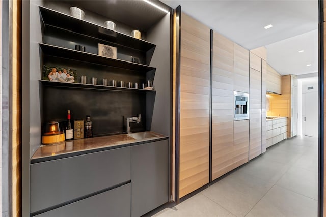 bar featuring tile walls, a sink, and light tile patterned flooring