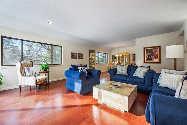 living area featuring baseboards, wood finished floors, and an inviting chandelier