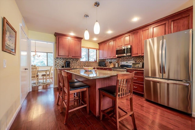 kitchen with stainless steel appliances, a kitchen island, tasteful backsplash, dark wood finished floors, and pendant lighting