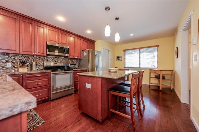 kitchen with dark wood-style floors, a kitchen bar, stainless steel appliances, and backsplash