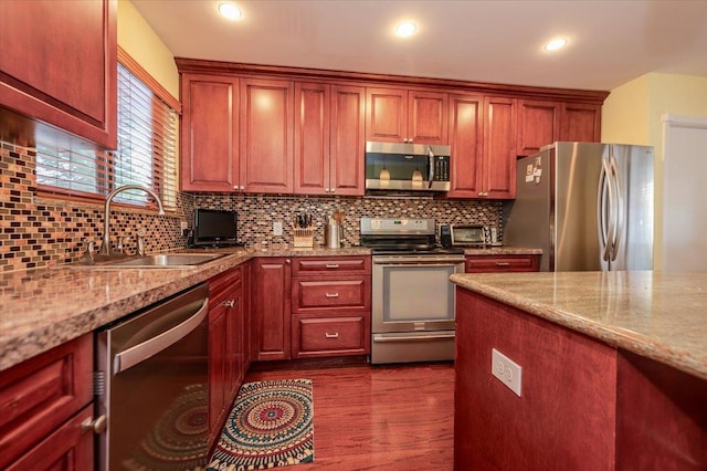 kitchen with backsplash, dark wood-style flooring, stainless steel appliances, and a sink