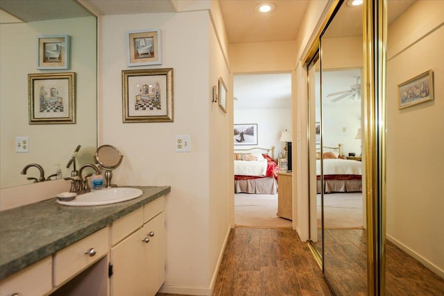 bathroom with ceiling fan, connected bathroom, wood finished floors, vanity, and baseboards