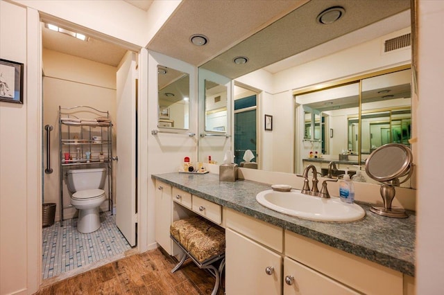 full bathroom featuring visible vents, vanity, wood finished floors, and toilet