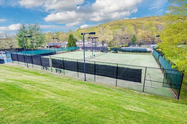 view of tennis court featuring a yard and fence