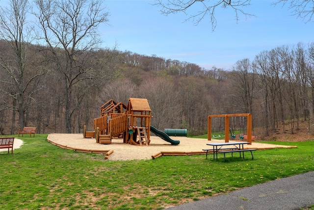 community play area with a lawn and a wooded view