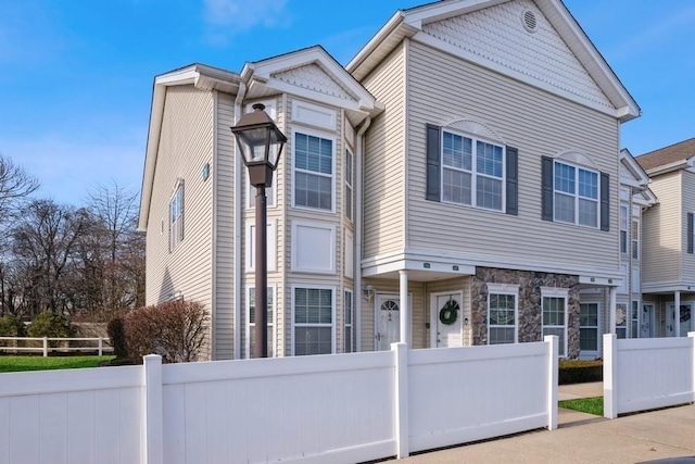 view of front of home featuring stone siding and a fenced front yard