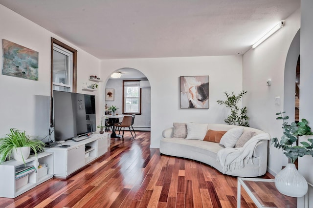 living area with arched walkways and wood finished floors