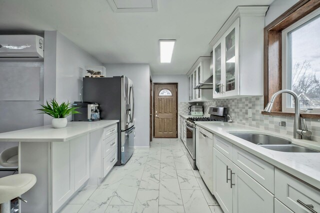 kitchen with tasteful backsplash, appliances with stainless steel finishes, marble finish floor, white cabinetry, and a sink