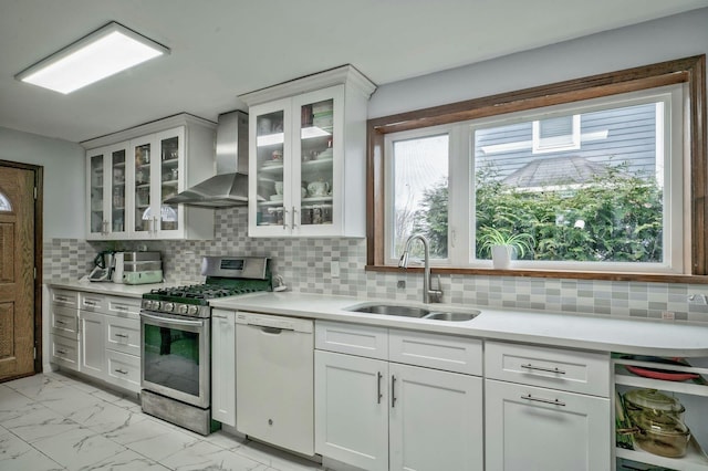 kitchen with white dishwasher, a sink, marble finish floor, wall chimney range hood, and gas range