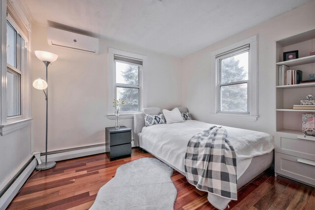 bedroom with a baseboard heating unit, a wall mounted air conditioner, wood finished floors, and a baseboard radiator