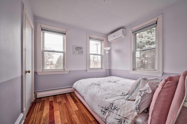 bedroom with wood finished floors, baseboard heating, and a wall mounted AC