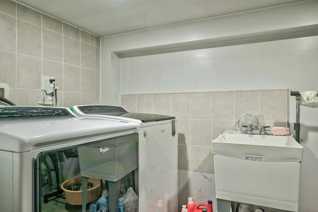 washroom with laundry area, a sink, tile walls, and washer and dryer