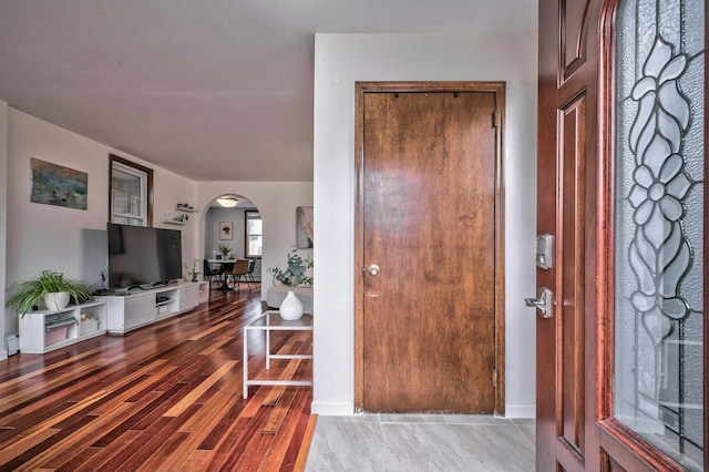 foyer entrance featuring arched walkways and wood finished floors