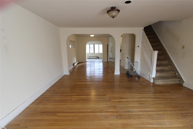 interior space with stairway, arched walkways, light wood-style flooring, and baseboards