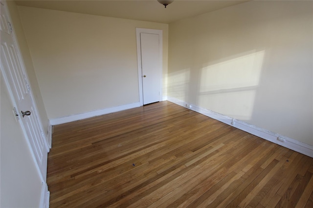 unfurnished room featuring baseboards and dark wood-type flooring