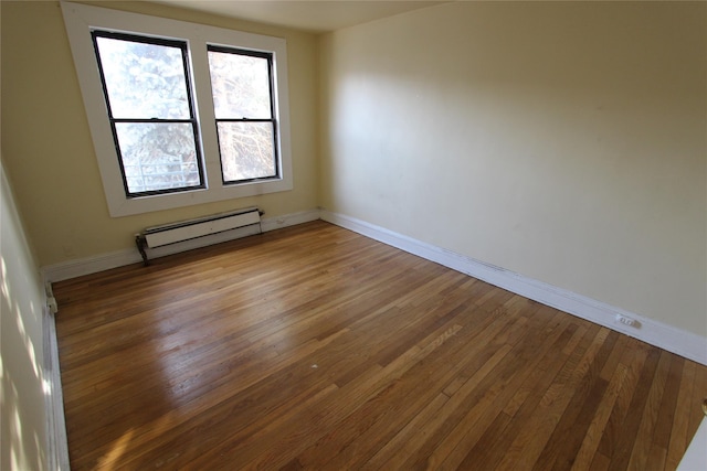 spare room featuring baseboards, baseboard heating, and wood finished floors