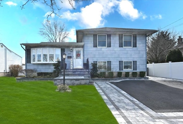 tri-level home featuring a front yard and fence