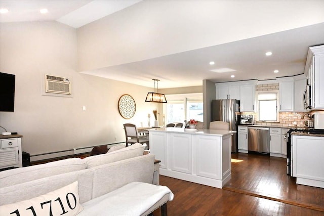 kitchen with decorative light fixtures, a wall unit AC, stainless steel appliances, open floor plan, and a kitchen island