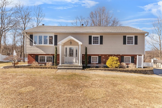 raised ranch featuring brick siding and a front lawn