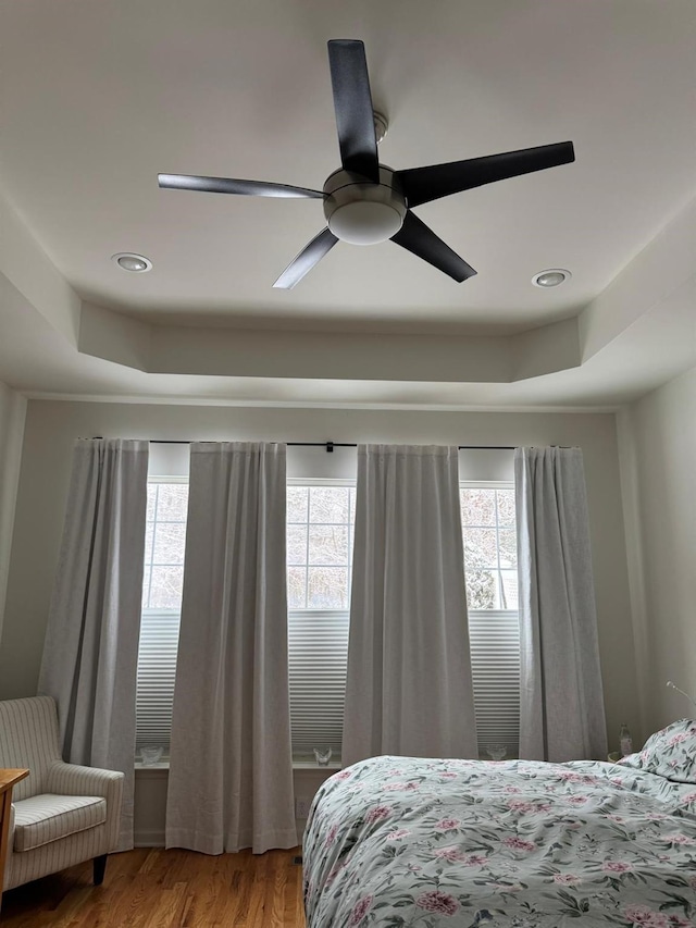 bedroom featuring a tray ceiling, wood finished floors, a ceiling fan, and recessed lighting