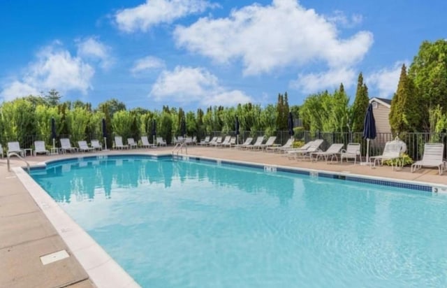 community pool with a patio and fence