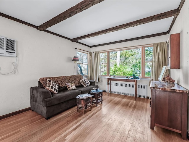 living room featuring light wood-style flooring, baseboards, a wall mounted AC, radiator, and beamed ceiling