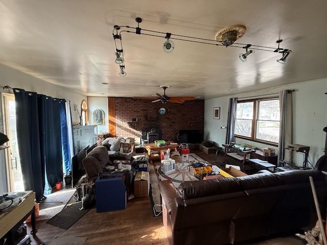 living room featuring a ceiling fan, wood finished floors, a wood stove, a fireplace, and track lighting