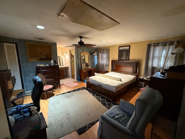 bedroom with attic access, visible vents, light wood finished floors, and a ceiling fan